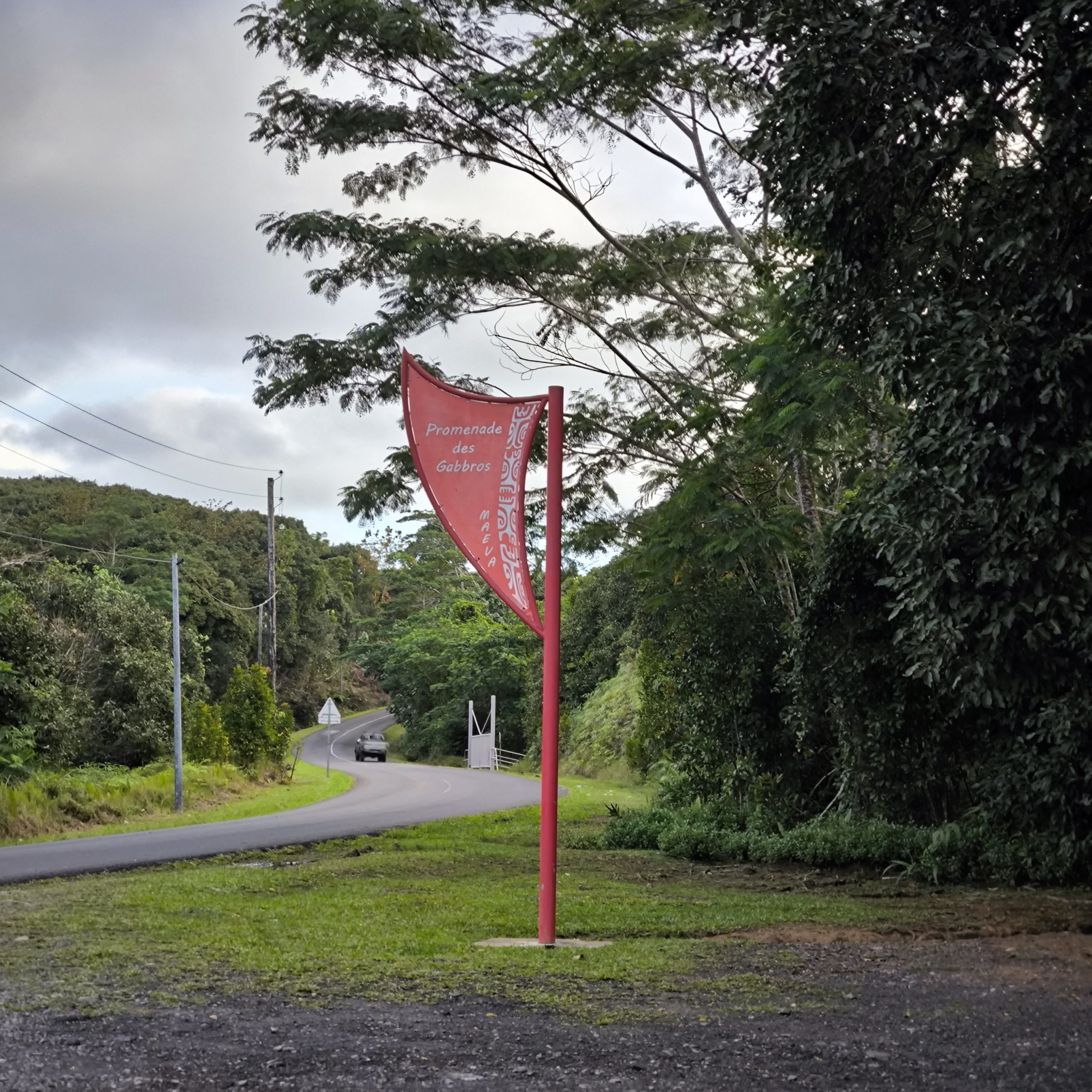 Panneau de la promenade des Gabbros à Raiatea, route et végétation tropicale