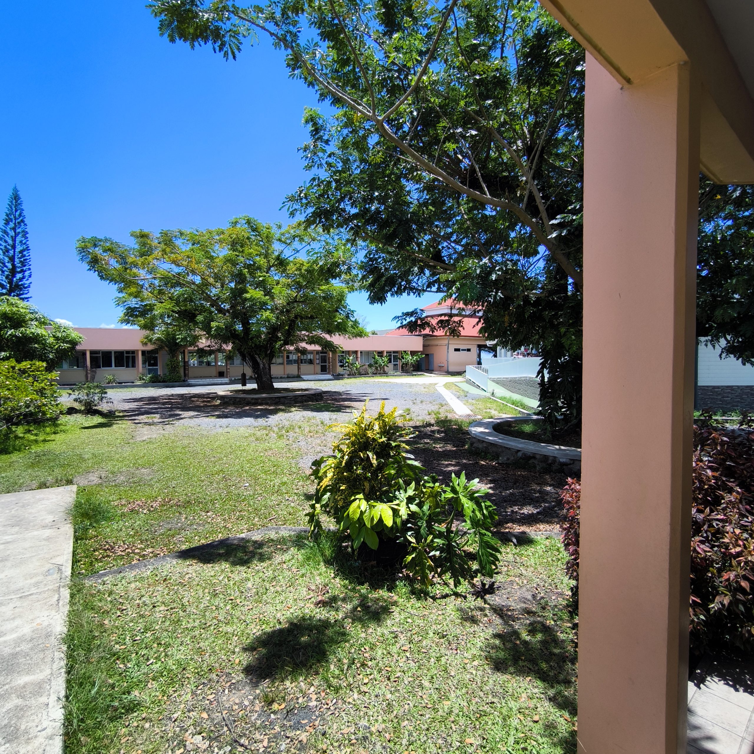 Cour de l'école d’Avéra à Raiatea avec les bâtiments et le grand arbre central